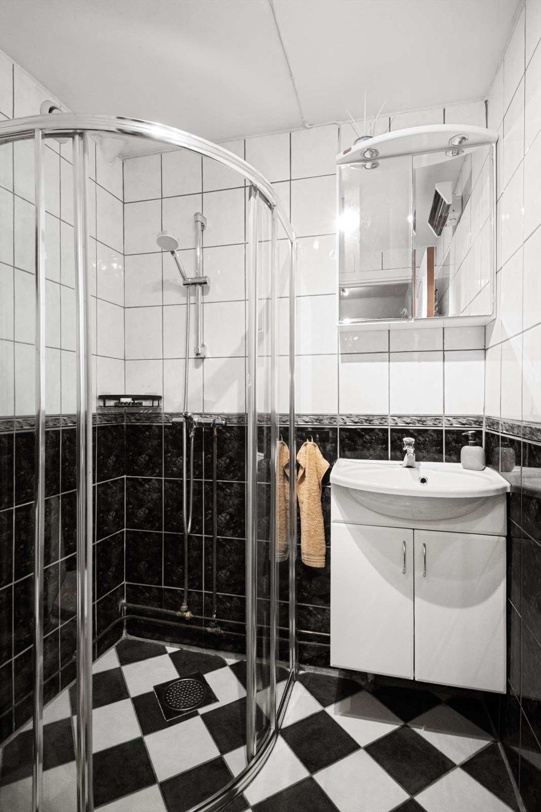 Flislagt baderom med dusjhjørne og servant med under- og overskap. Galleribilde