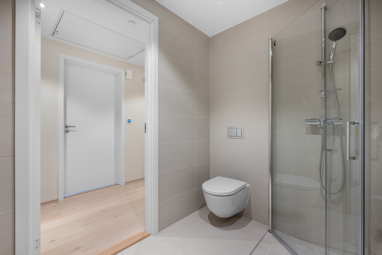 Den nordiske stilen videreføres på badet med matte fliser i storformat i en lys sandfarge på gulv og vegg. Galleribilde