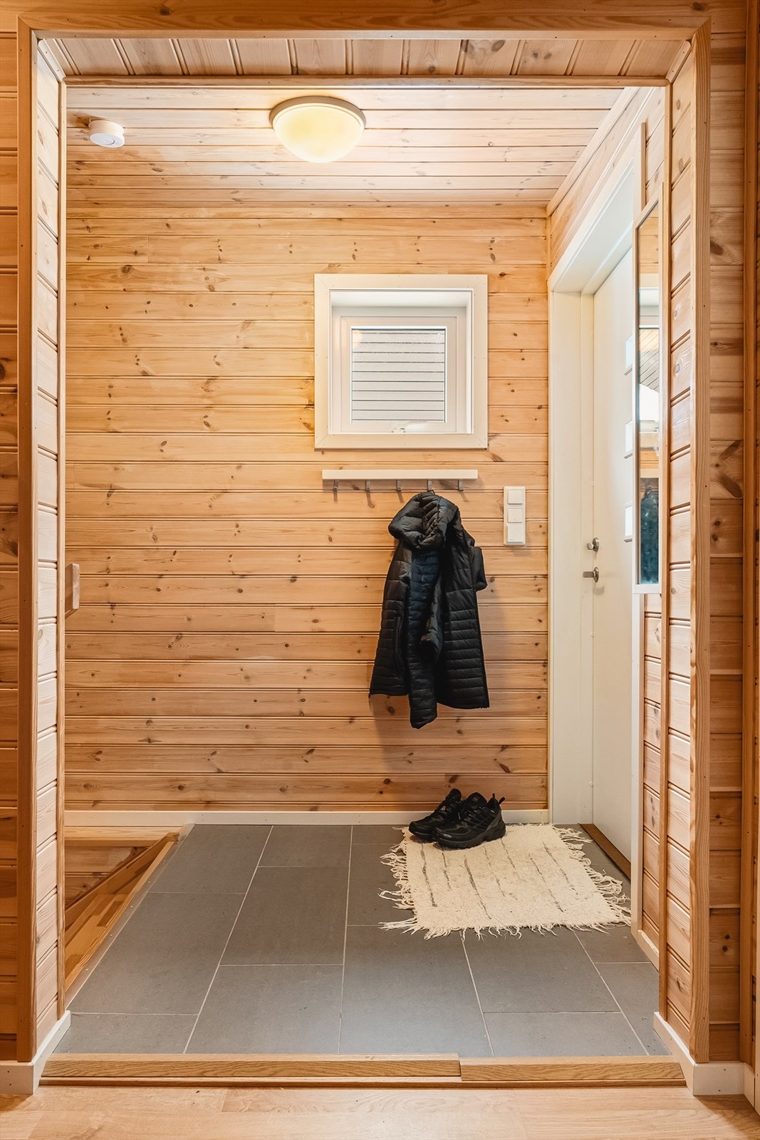 Inngangsparti til hytten tar deg inn i 2. etasje. Panel på vegger og i himling, flislagt gulv med varmekabler. Trapp (t.v.) ned til 1. etasje. Galleribilde
