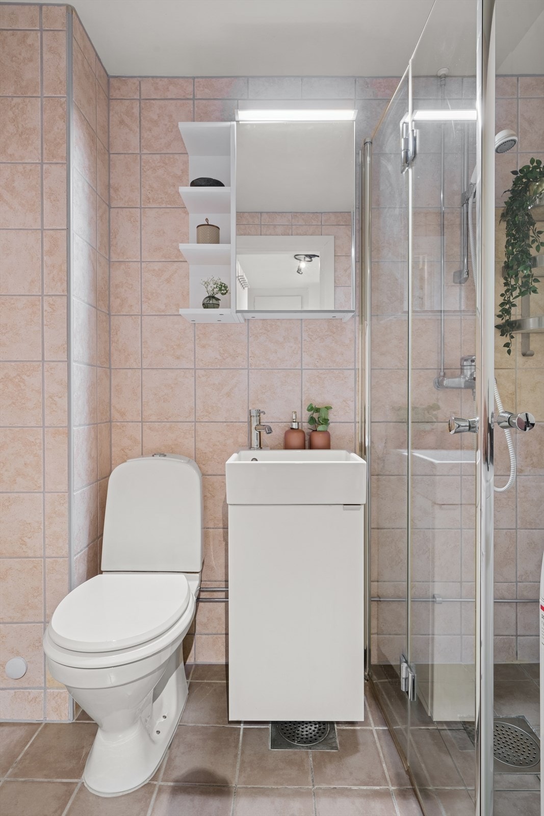 Badet har innredning med nedfelt servant, vegghengt toalett, dusjhjørne med glassvegger og opplegg for vaskemaskin. Galleribilde