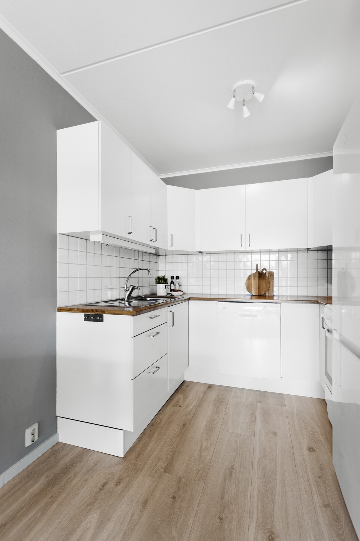 Kjøkkeninnredning med slette hvite skuff- dørfronter fra Sigdal kjøkken, integrerte hvitevarer som oppvaskmaskin, frittstående stekevon og kjøleskap Galleribilde