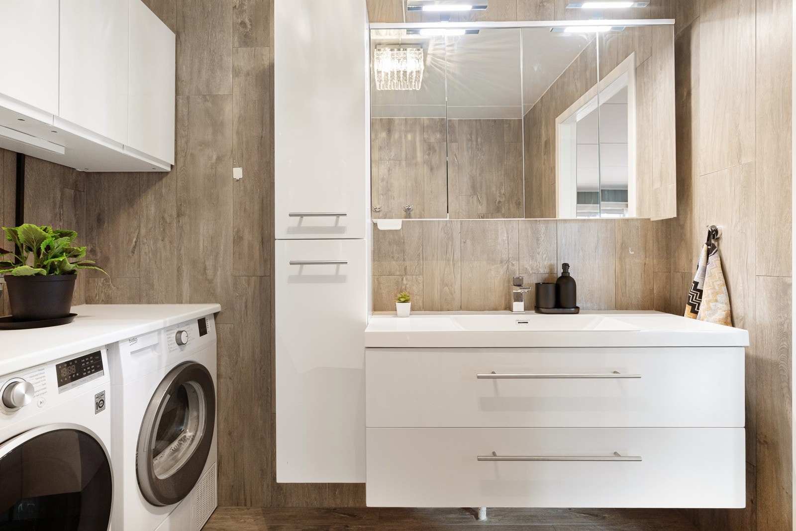 Lekker baderomsinnredning med gode oppbevaringsmuligheter og smart plasstilpasset nisje for vaskemaskin og tørketrommel. Galleribilde