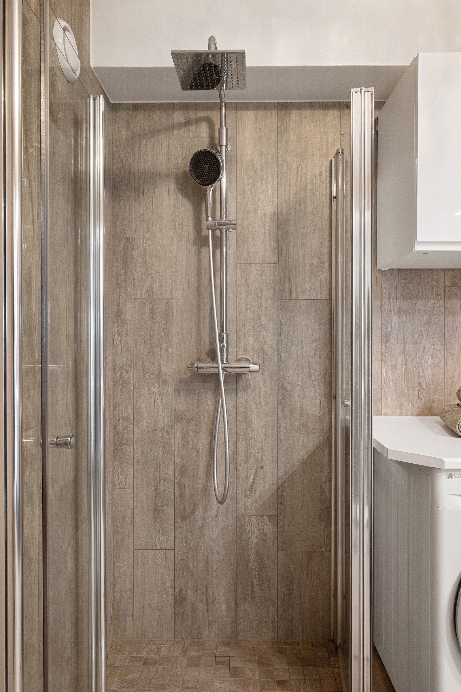 Dusjsone med innfellbare dusjdører og vegghengt dusjgarntiyr med regnfallsdusj og hånddusj. Galleribilde