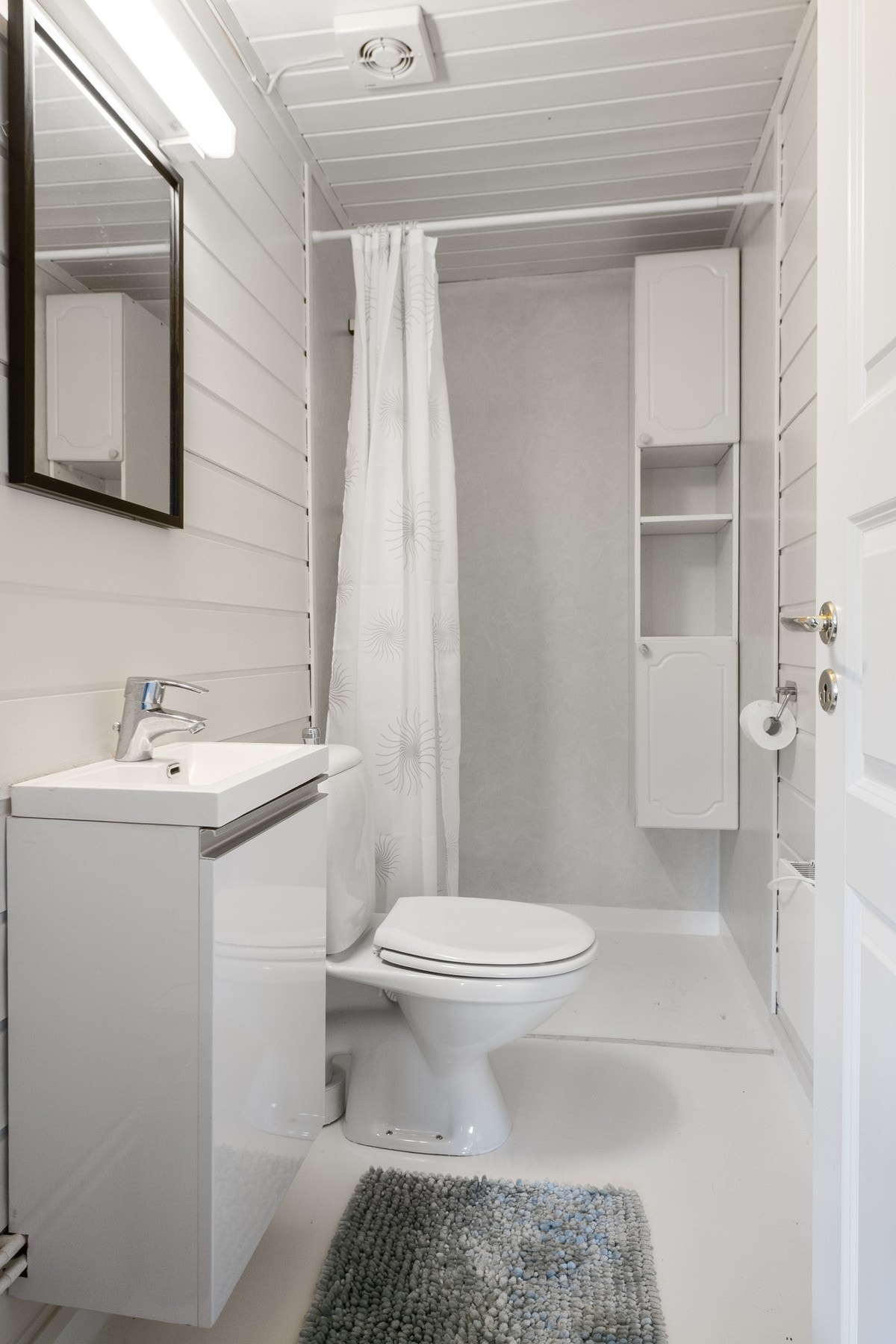 Hytten har to bad. Bad til høyre: Dusjhjørne med forheng. Vegghengt dusjarmatur og gulvstående toalett. Speil med overlys. Mekanisk avtrekksvifte i himling. Galleribilde