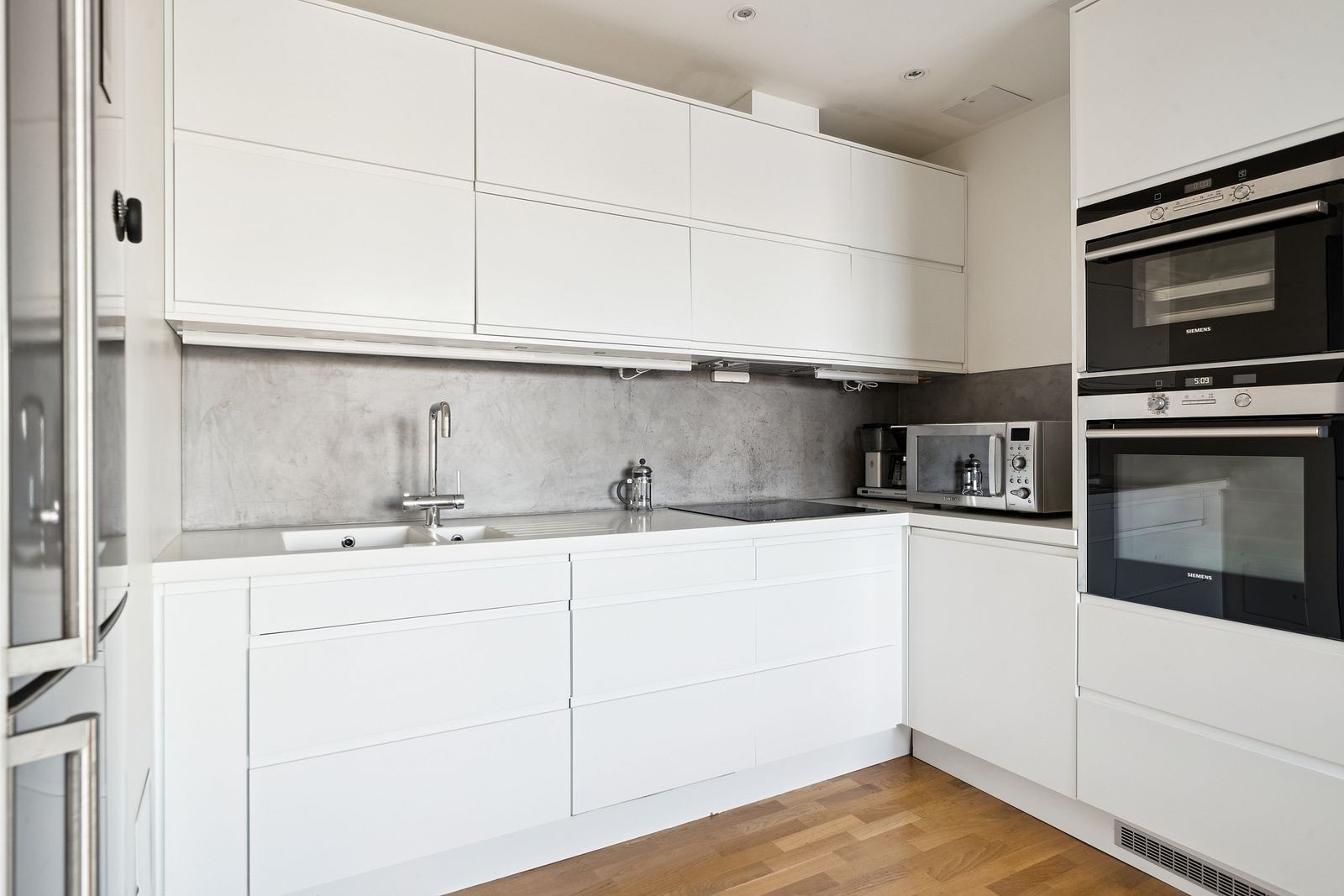 Moderne kjøkken med integrerte hvitevarer og stålfarget frittstående kombiskap og micro. Galleribilde