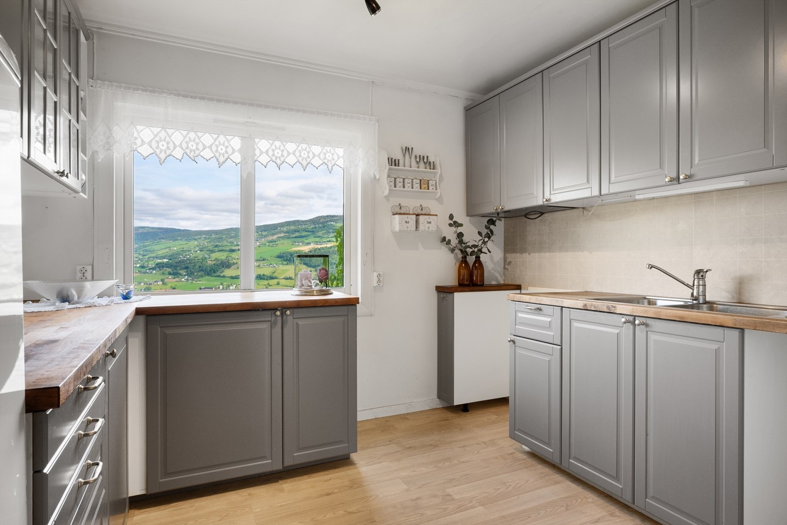 Kjøkkenet har tidløs, grå innredning med profilerte fronter og benkeplate i heltre. Galleribilde