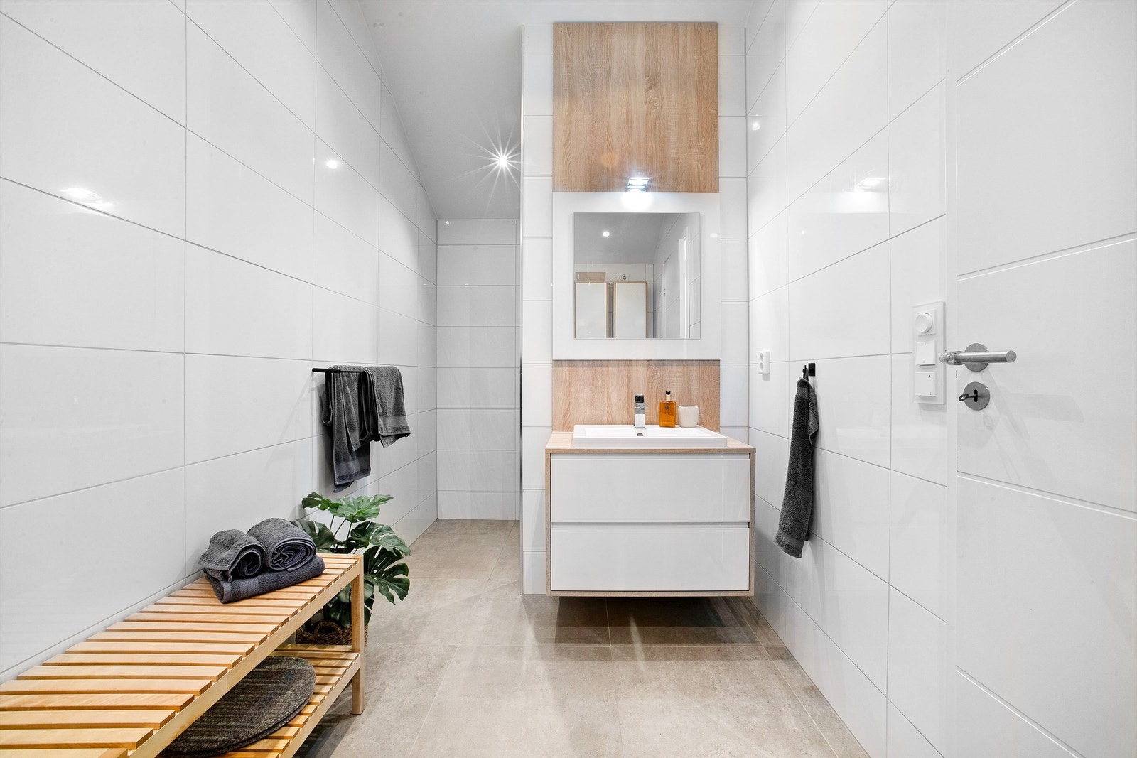 Flislagt bad med dusjsone bak servant. Galleribilde