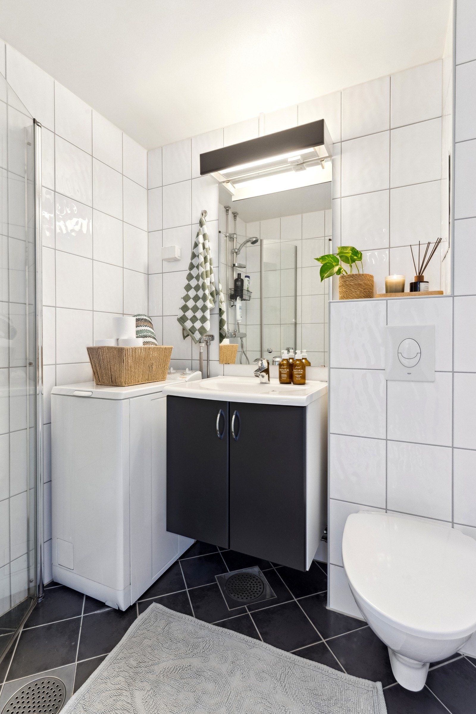 Delikat bad/wc med varmekabler, opplegg for vaskemaskin, servant med underskap og veggmontert klosett. Galleribilde