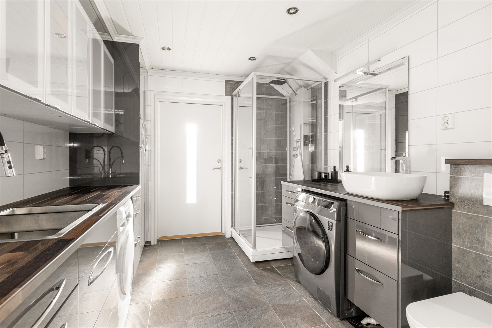 Praktisk bad/vaskerom fra 2014 med egen utgang og opplegg for vaskemaskin. Vaskerommet har flislagt gulv med varmekabler og baderomsplater på vegger. Galleribilde