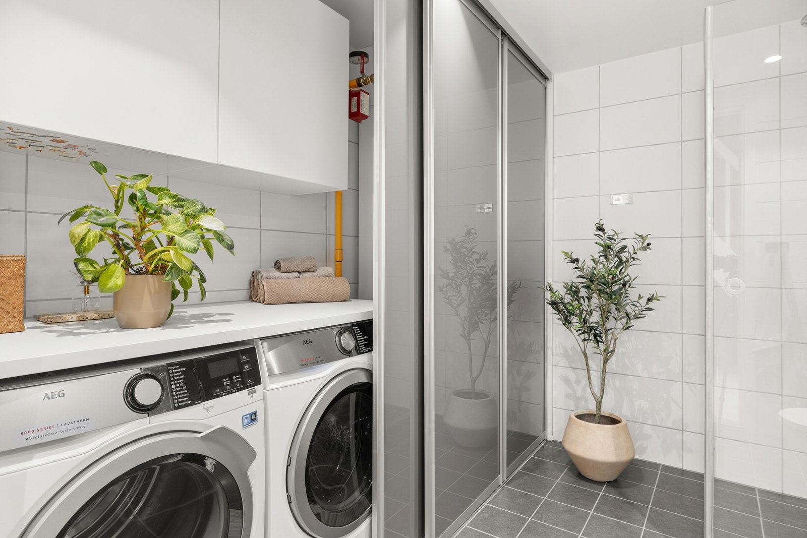 Baderommet er stilrent innredet med praktiske skyvedørsfronter som skjuler vaskmaskin og tørketrommel. Galleribilde
