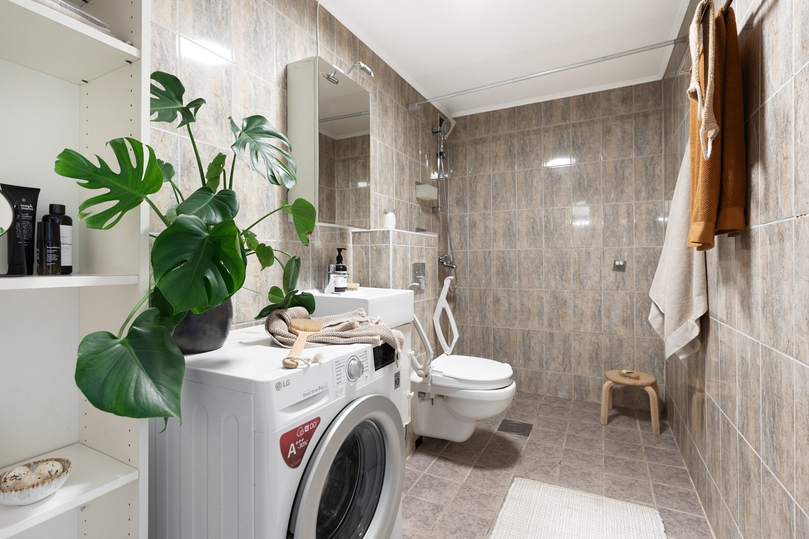 Stort flislagt bad hvor dere får alt dere trenger med praktisk dusjplass, servant med underskap,
speilskap med lys over, opplegg for vaskemaskin og veggmontert wc. Galleribilde