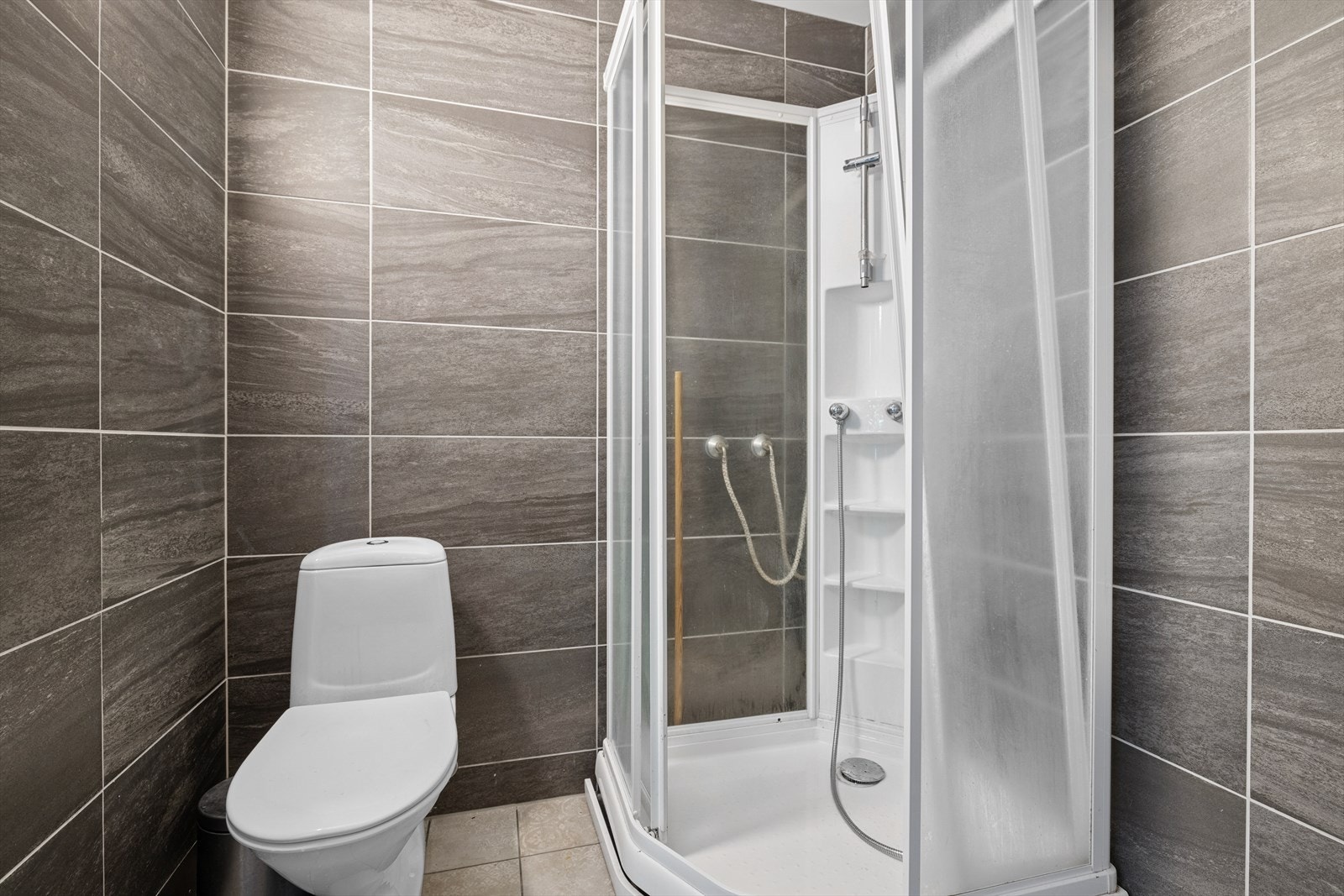 På badet er det dusjkabinett, toalett og baderomsinnredning Galleribilde