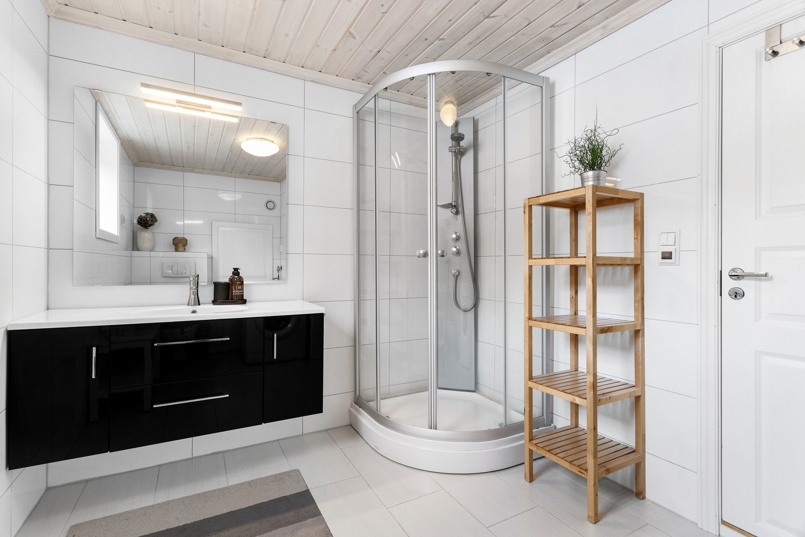 Delikat, helfliset baderom med dusjkabinett, vegghengt toalett og servant med innredning. Klassiske fliser som holder seg tidsriktige over tid Galleribilde