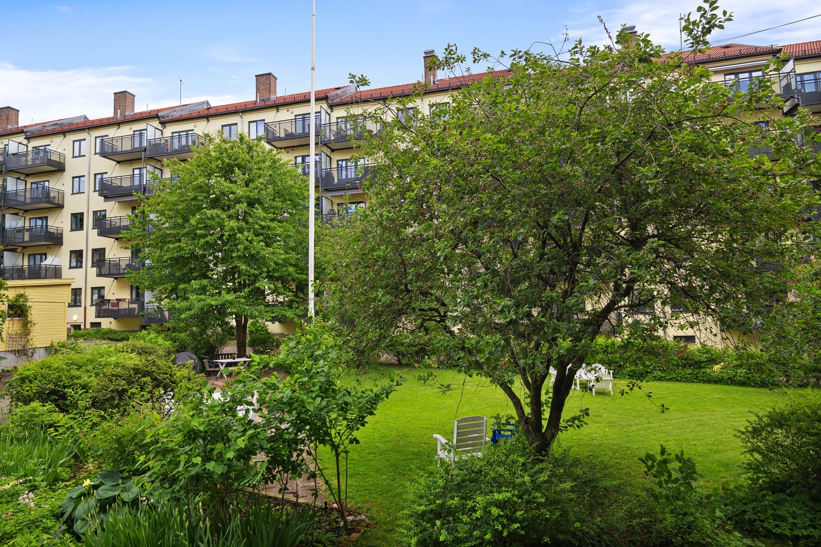 - Hyggelig utsikt mot gårdsrommet med plen, planter, busker og trær - Galleribilde