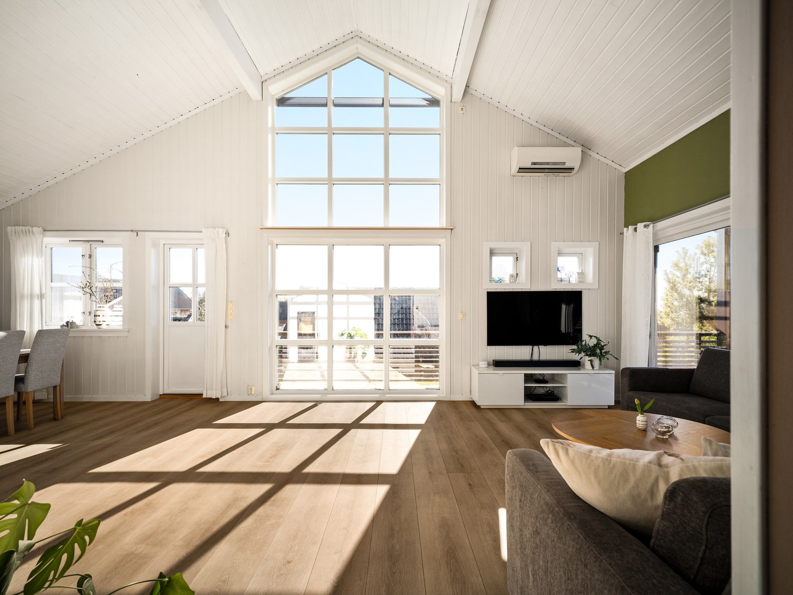 Gavlveggens vindussøyle fremhever den luftige takhøyden og fyller stuen med naturlig lys. Galleribilde