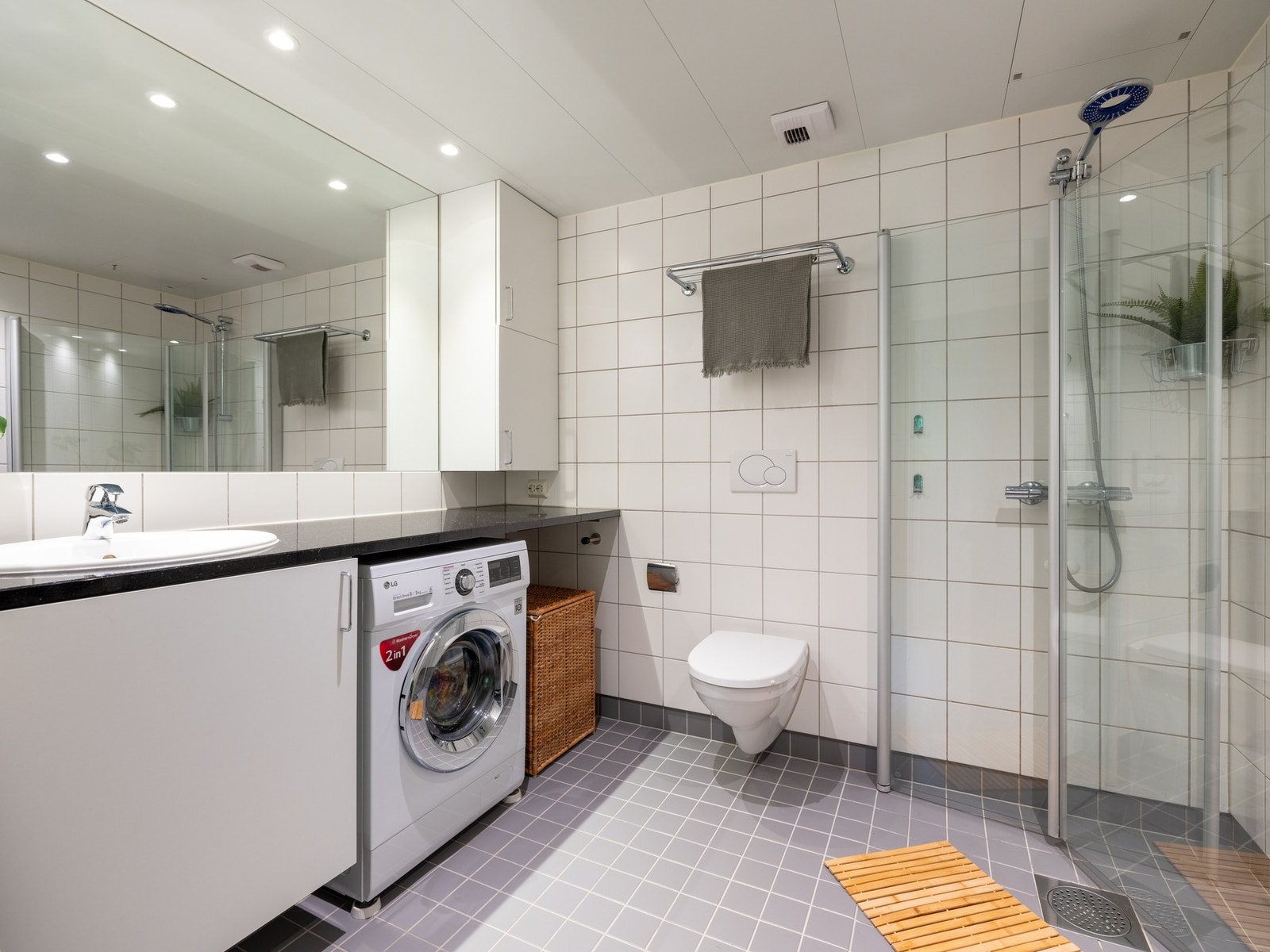 Boligens baderom er lyst og pent, med varme i gulv og downlights i himling. Plassbesparende nisje under benkeplaten for vaskemaskin og tørketrommel. Galleribilde