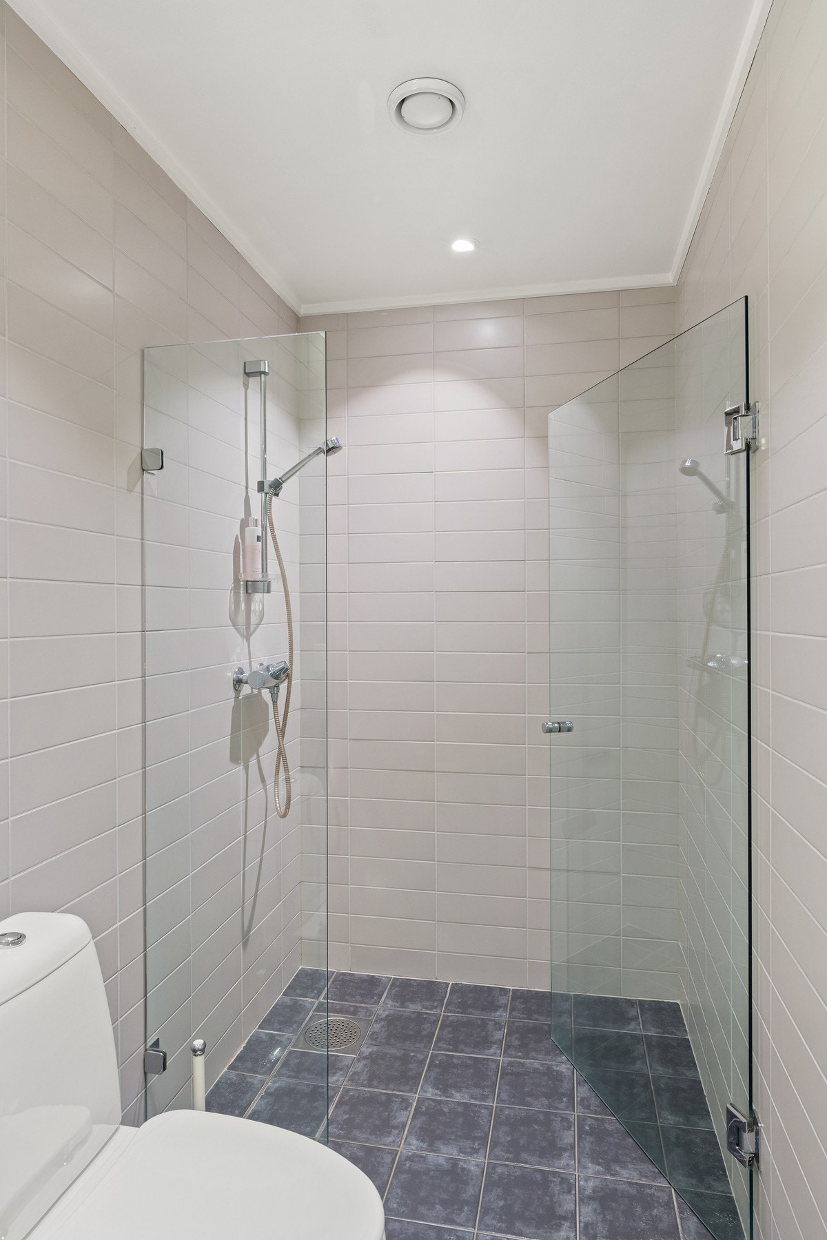 På det andre badet er det lyse fliser på veggene, downlights i himlingen og grå fliser på gulv med gulvvarme. Galleribilde