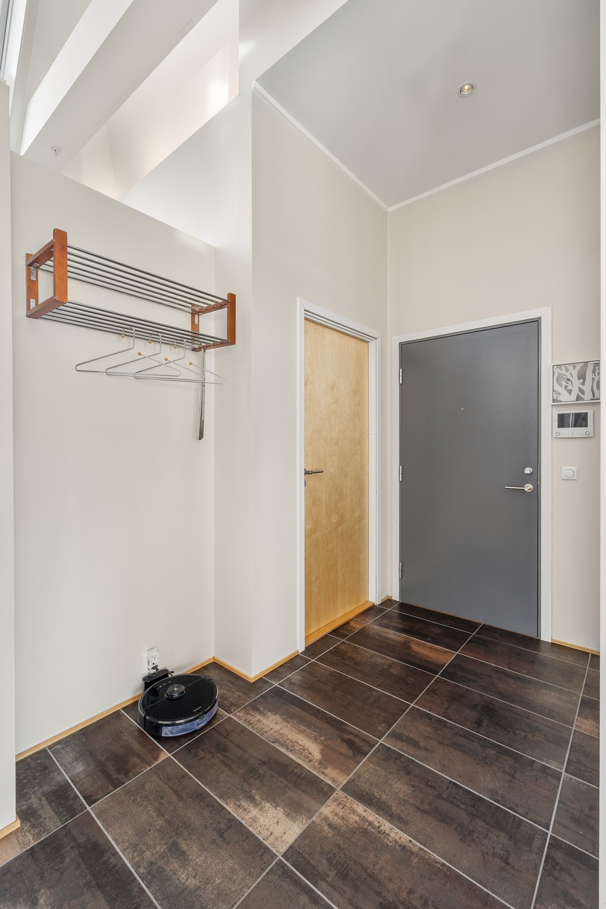 Vel inne blir vi ønsket velkommen i en pen entré med lysmalte vegger, downlights i himlingen og brune fliser på gulvet. Galleribilde