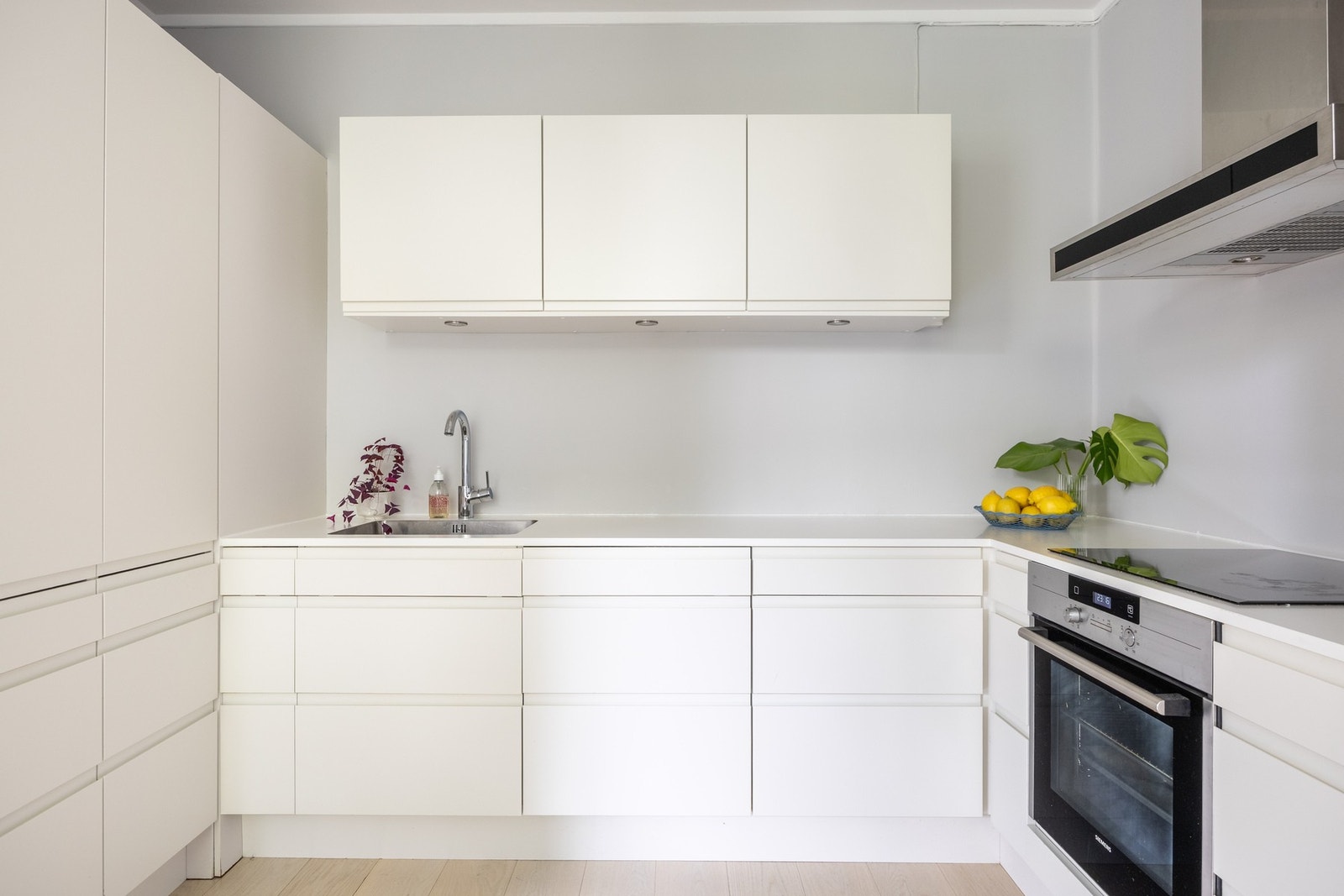 Kjøkkenet har fronter i matt hvit utførelse og benkeplater av kompaktlaminat med planlimt rustfri oppvaskkum. Galleribilde