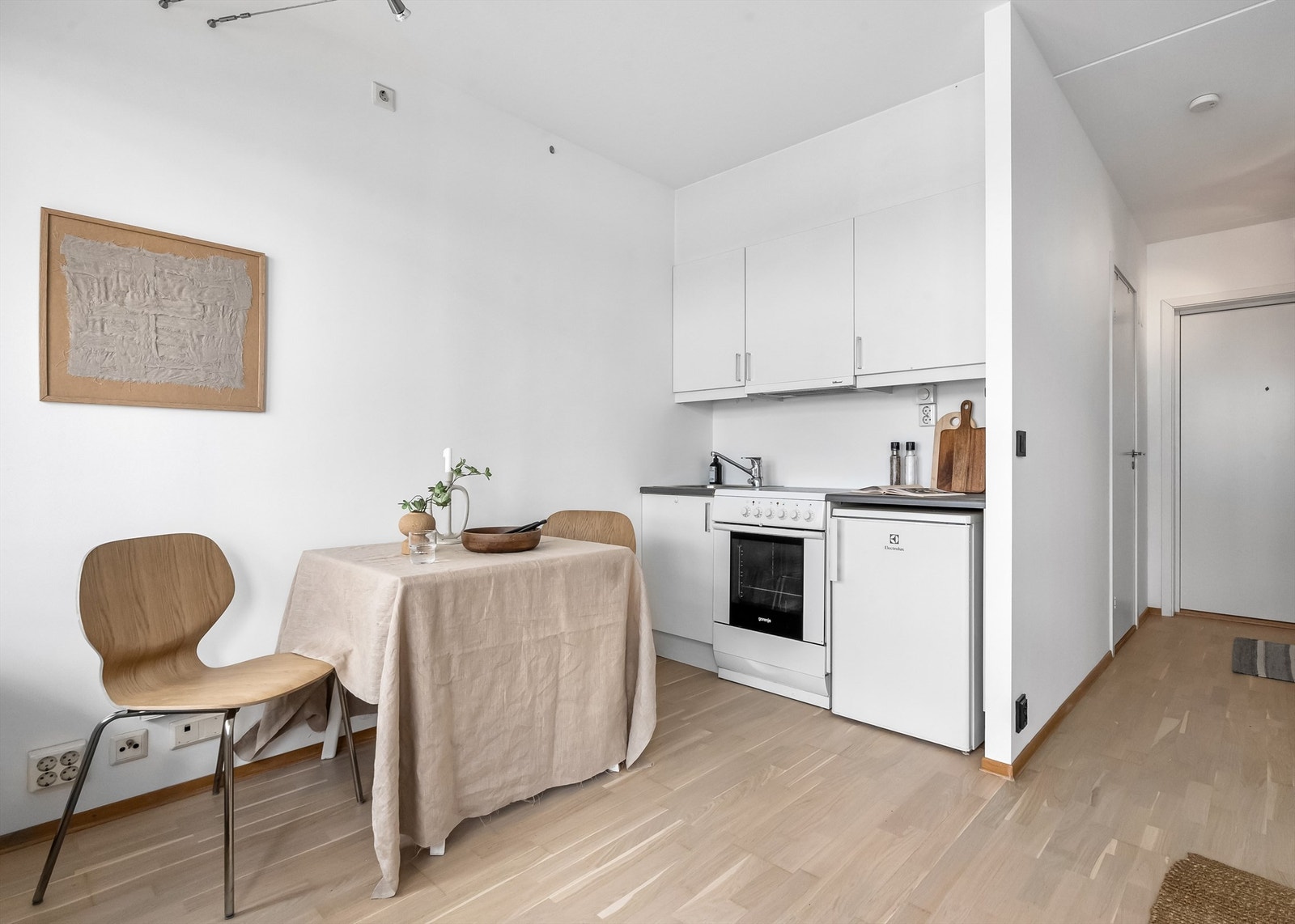 Lys kjøkkeninnredning fra byggeår med kjøleskap og komfyr. Galleribilde