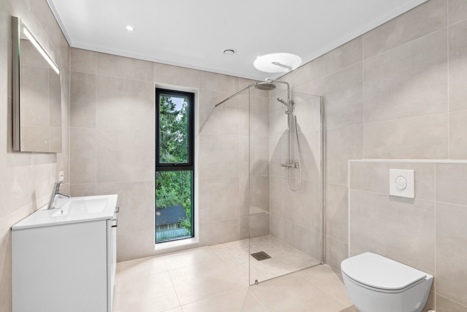 På badet er det dusjnisje, vegghengt toalett og servant med innredning Galleribilde