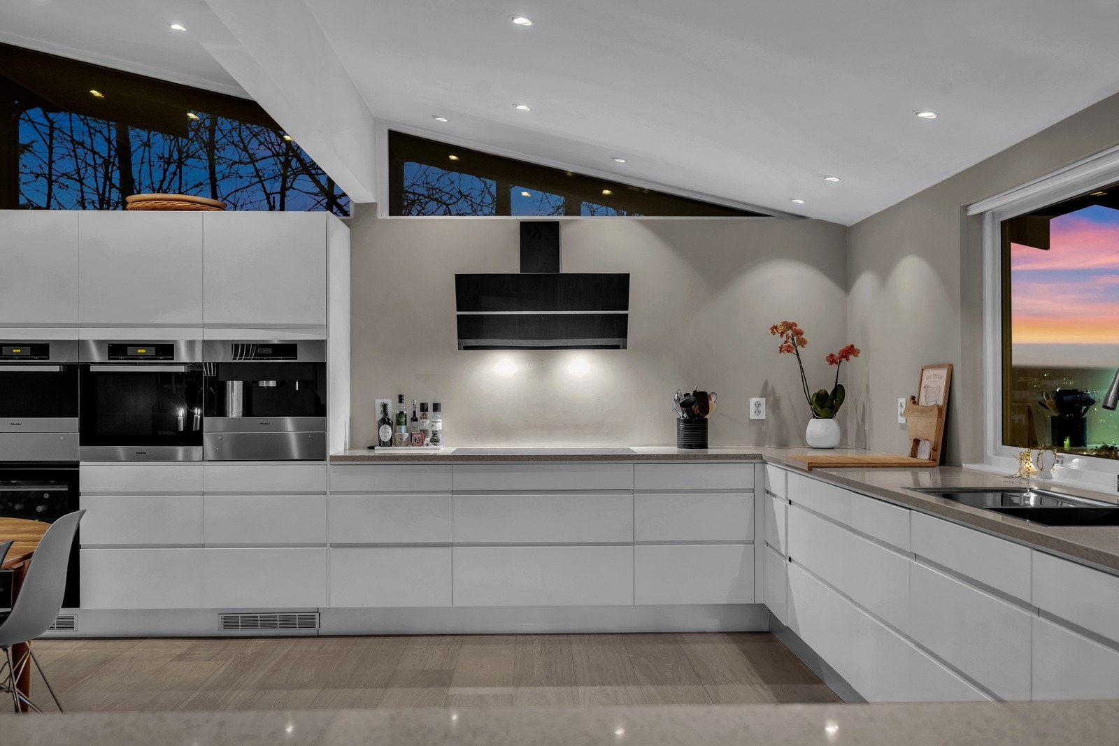 Stilren kjøkkeninnredning med innfreset grepslist, rette linjer som gir et rent uttrykk og rikelig med oppbevaringsplass i skap og skuffer. Galleribilde