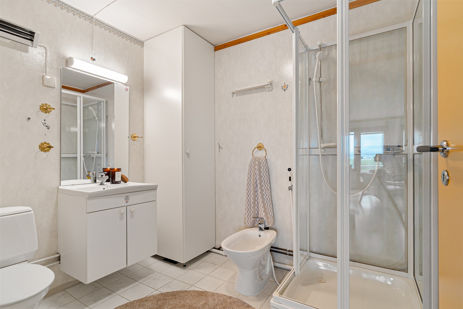 Det lyse baderommet har dusjkabinett, bide, toalett og servant med skap, speil og belysning. Galleribilde