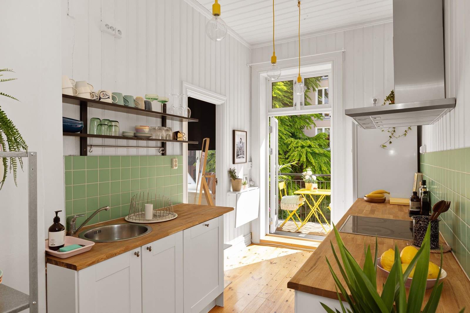 Pen og tidløs kjøkkeninnredning med lyse profilerte fronter og benkeplate av tre med nedfelt oppvaskkum. Galleribilde