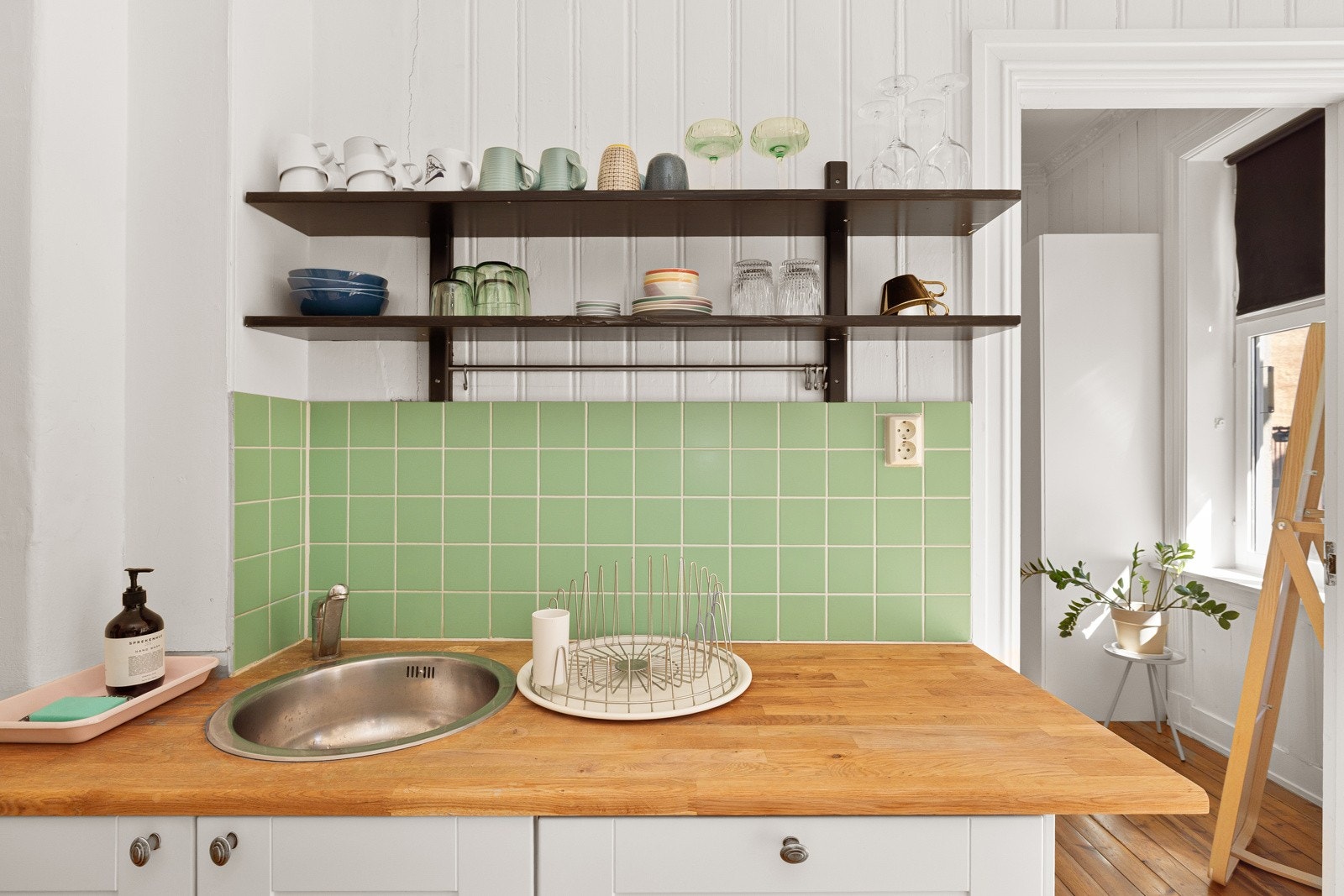 Både fint og praktisk med nydelig grønne fliser i benkeryggen, samt vegghengte hyller for oppbevaring og dekor. Galleribilde