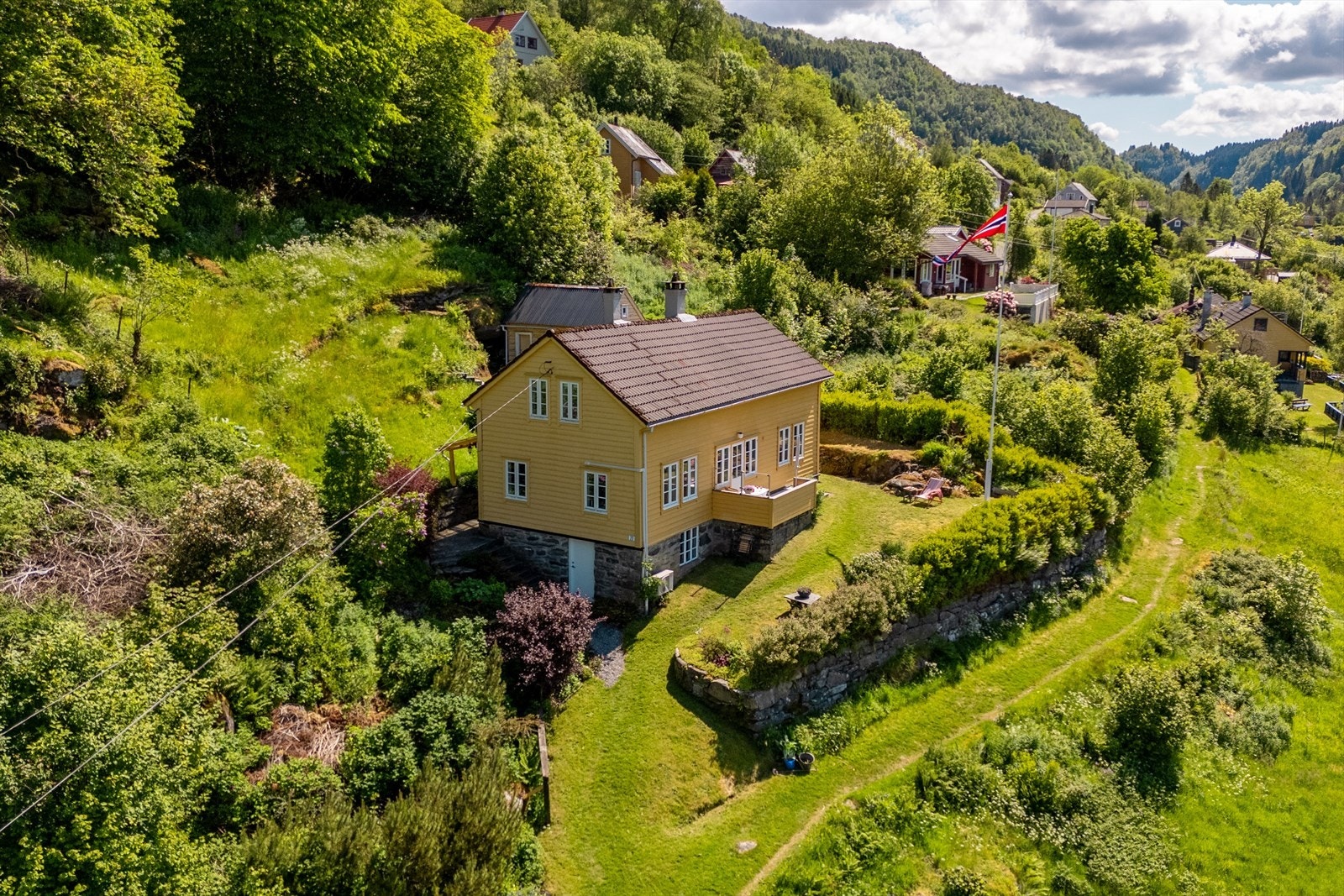 Eiendommen ligger fint hevet over den gamle bygdeveien foran med flott natursteinsmur i front Galleribilde