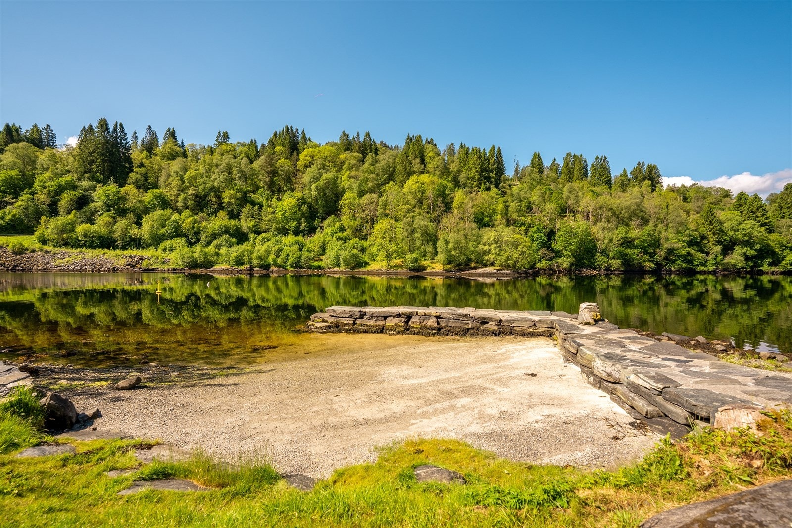 Offentlig badeplass i Mjøsvågen rett ved siden av naustet med sandstrand og stupebrett Galleribilde