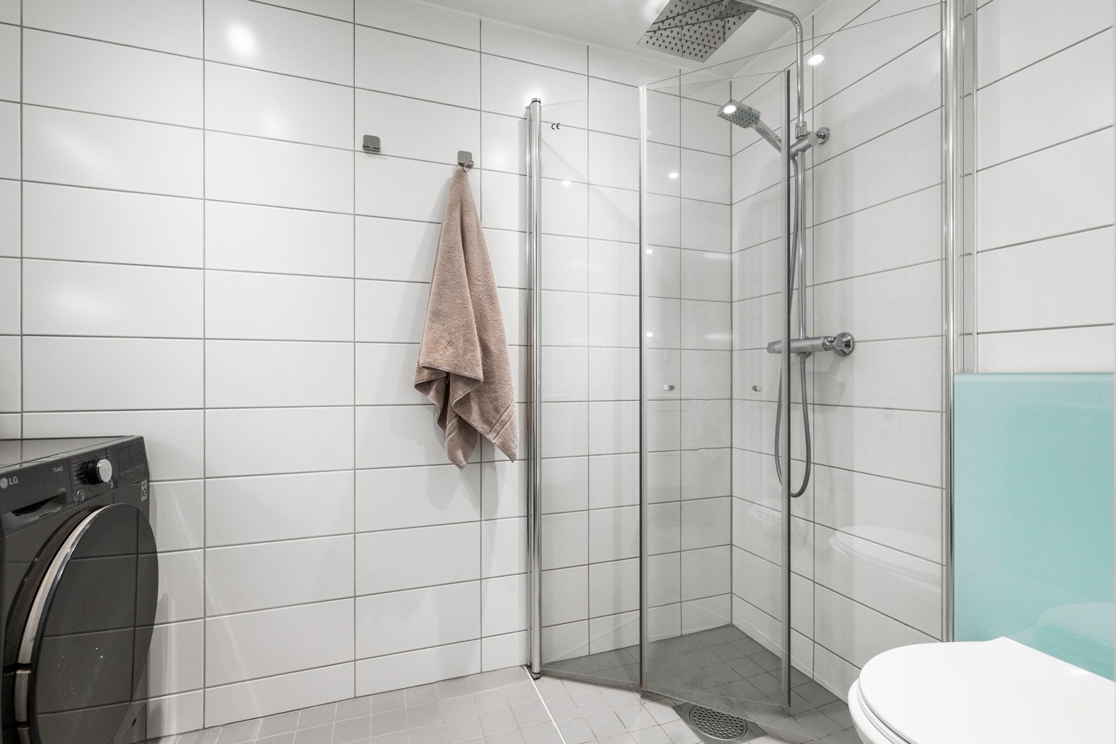 Badet har en stilren dusjløsning med glassvegger og regnfallsdusj, som gir en behagelig spa-følelse i hverdagen. Fliser på gulv og vegger gir et helhetlig og moderne uttrykk. Galleribilde