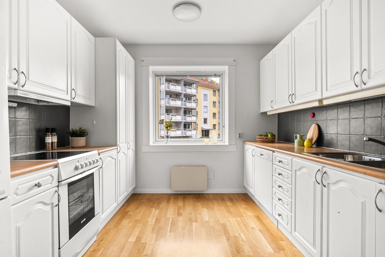 Kjøkkenet har profilerte fronter med rikelig benkeplass. Belysning under overskap og fliser mellom over og underskap Galleribilde