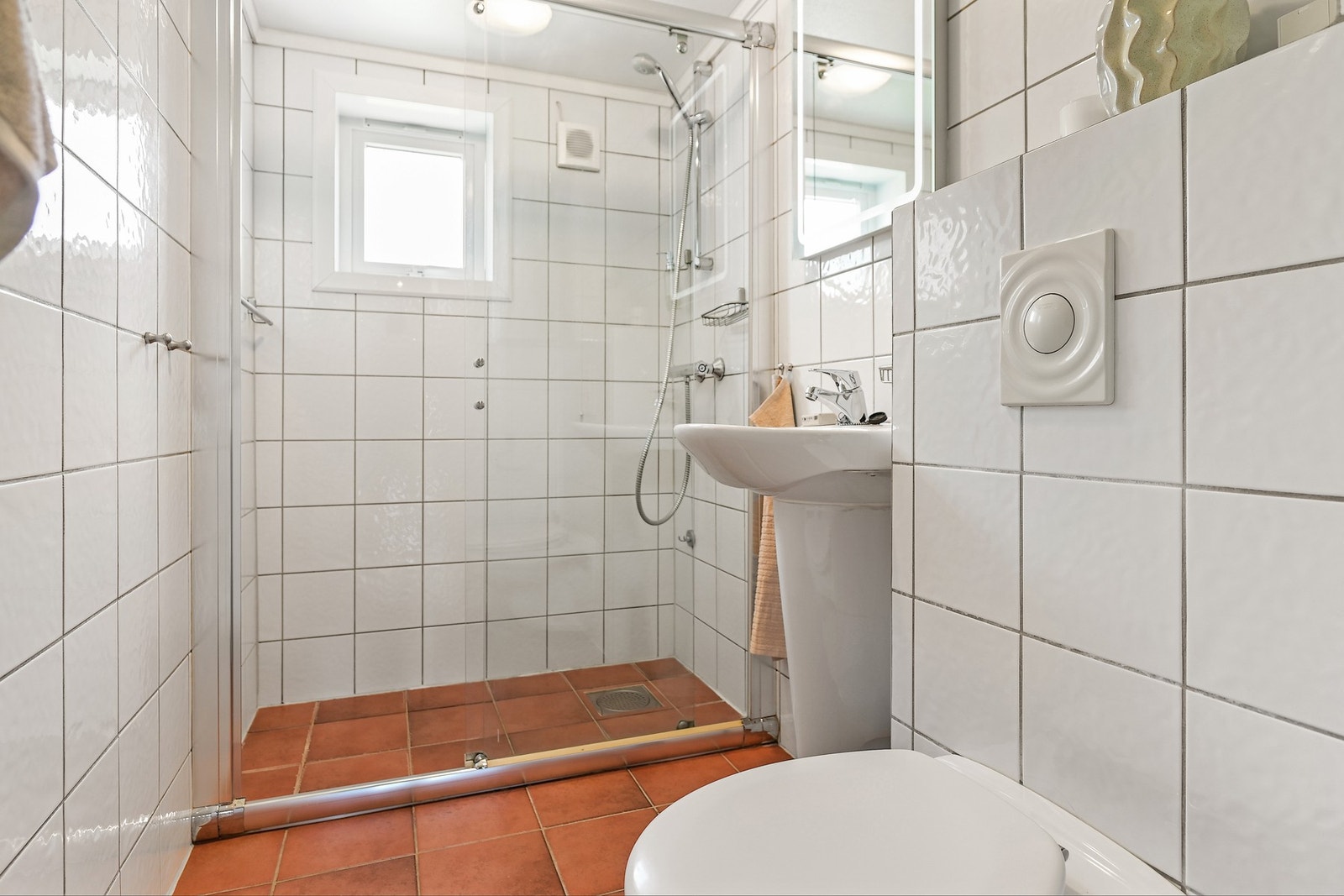 Badet er flislagt med varmekabler i gulv og er innredet med dusjnisje, vegghengt toalett og servant med speil og belysning. Galleribilde