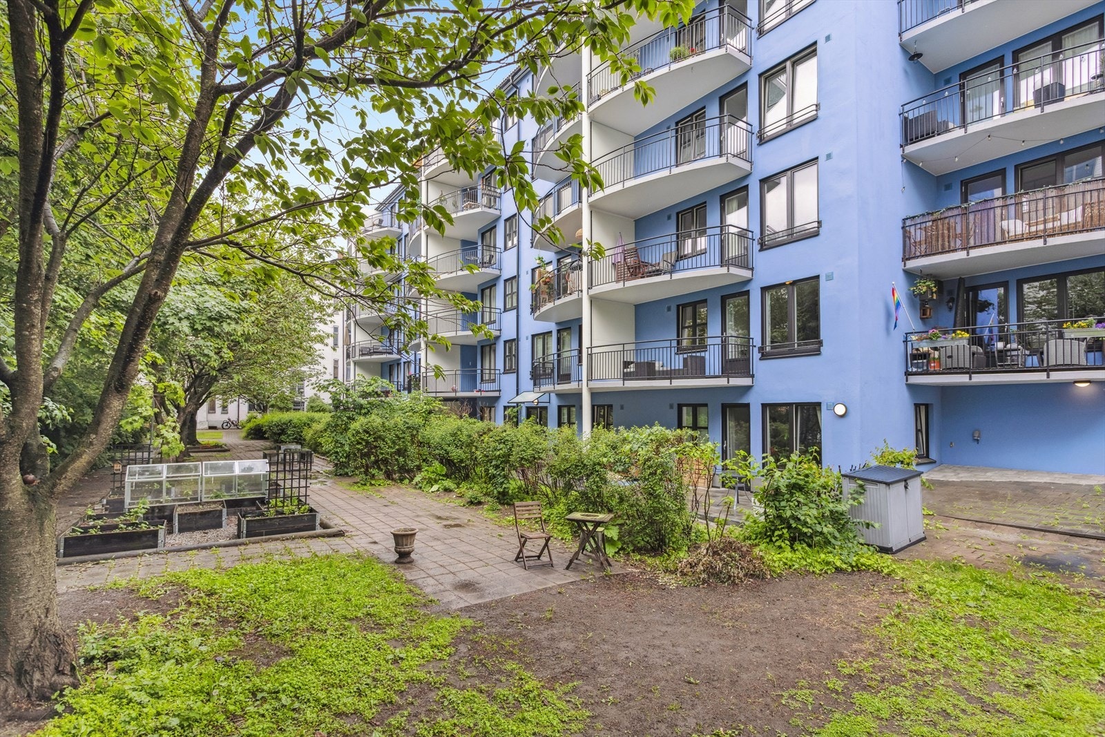 Bakgården er frodig beplantet og har flere sitteplasser og plantekasser til dyrking Galleribilde