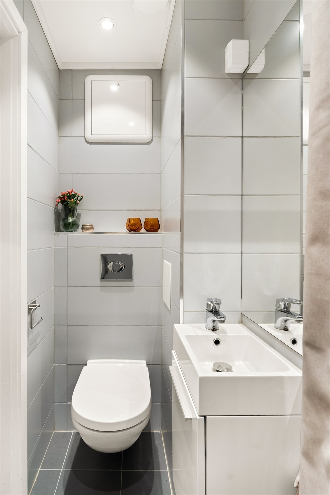 Baderommet er innredet med glatt baderomsinnredning med heldekkende servant nedfeldt i underskap, speil m/lys, veggmontert toalett og dusjhjørne. Galleribilde