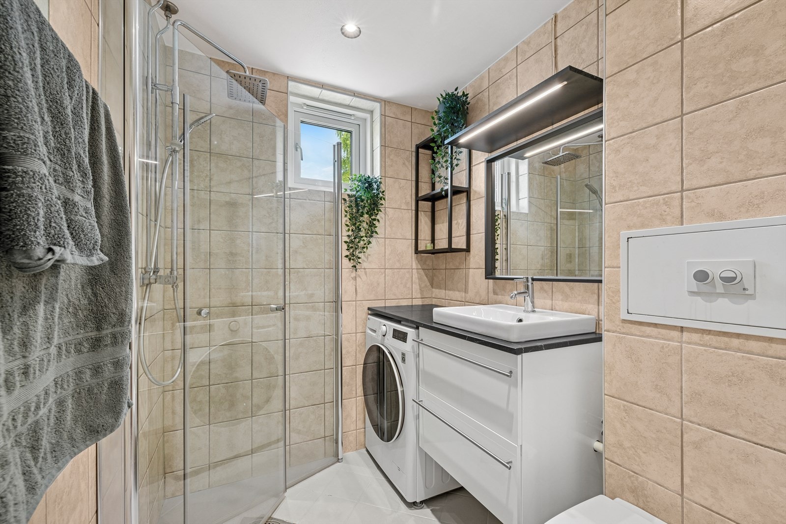 Her finner du en benkeplate i laminat med nedfelt servant, glatte skapfronter i høyglans, veggmontert toalett og en praktisk dusjsone. Galleribilde