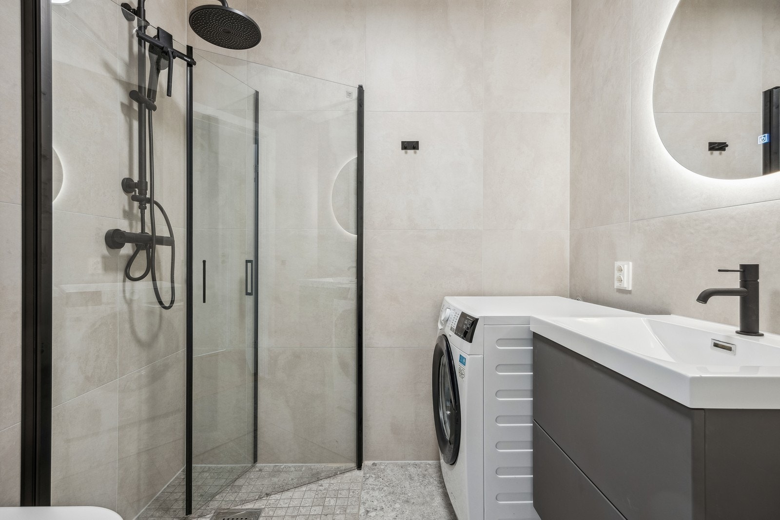 Flislagt bad med vaskemaskin, servant, dusj og toalett. Det er stikk til tørketrommel. Galleribilde