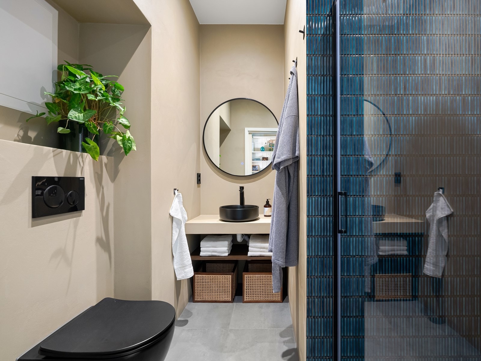 Baderomsinnredningen består av servant med hyller under og speil, vegghengt toalett og nedsenket dusj med glassdører. Galleribilde