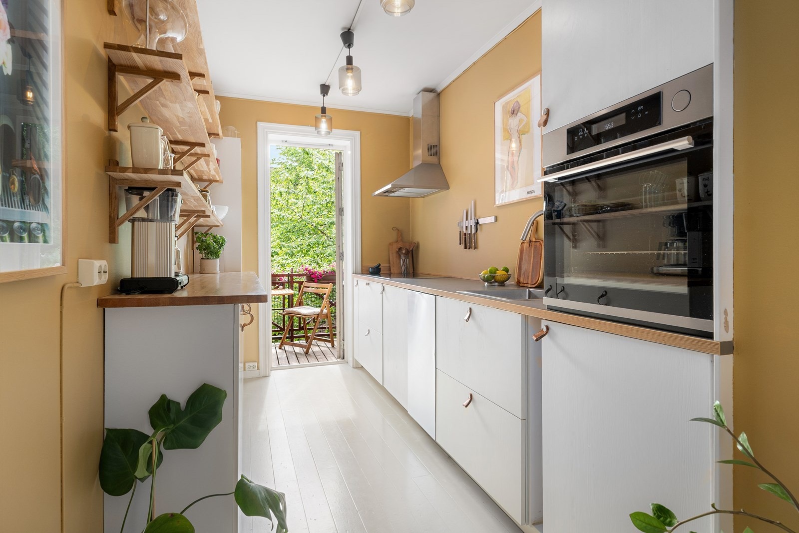 Kjøkkenet er stilrent med lyse, malte, MDF plater som dørfronter og lyse, glattlakkerte fronter, samt skapstammer fra IKEA med dels laminat og heltre benkeplate. Her er det rikelig med arbeidsflate for den som skal kokkelere. Galleribilde