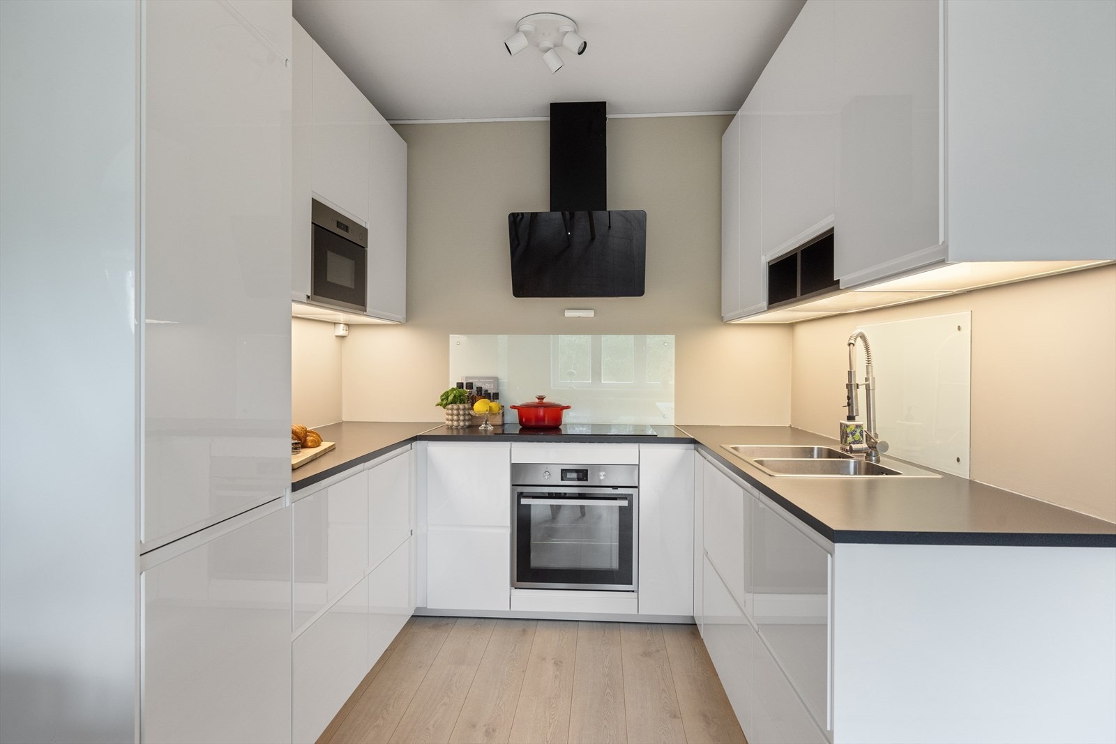 Kjøkkeninnredningen er utført med høyglans fronter, laminat benkeplate med oppvaskkum og glassplater over benk. Galleribilde