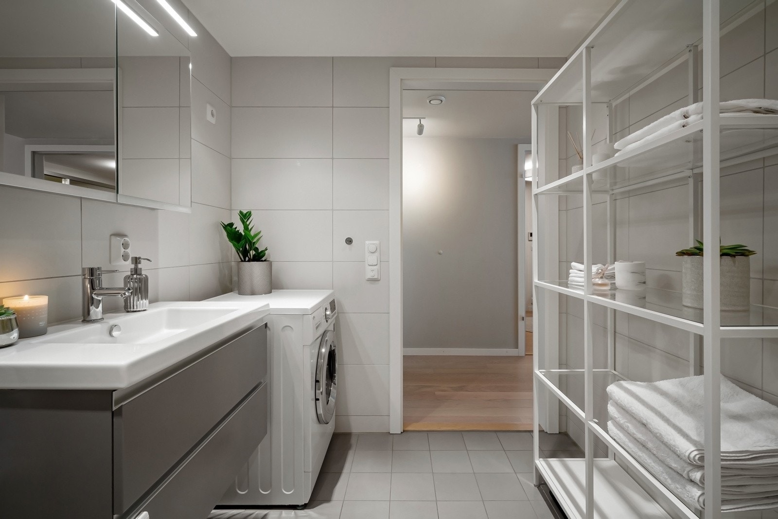 Flislagt baderom utført i lyse farger fra byggeår med vannbåren varme i gulv. Vegghengt servant og skap med speilfronter Galleribilde