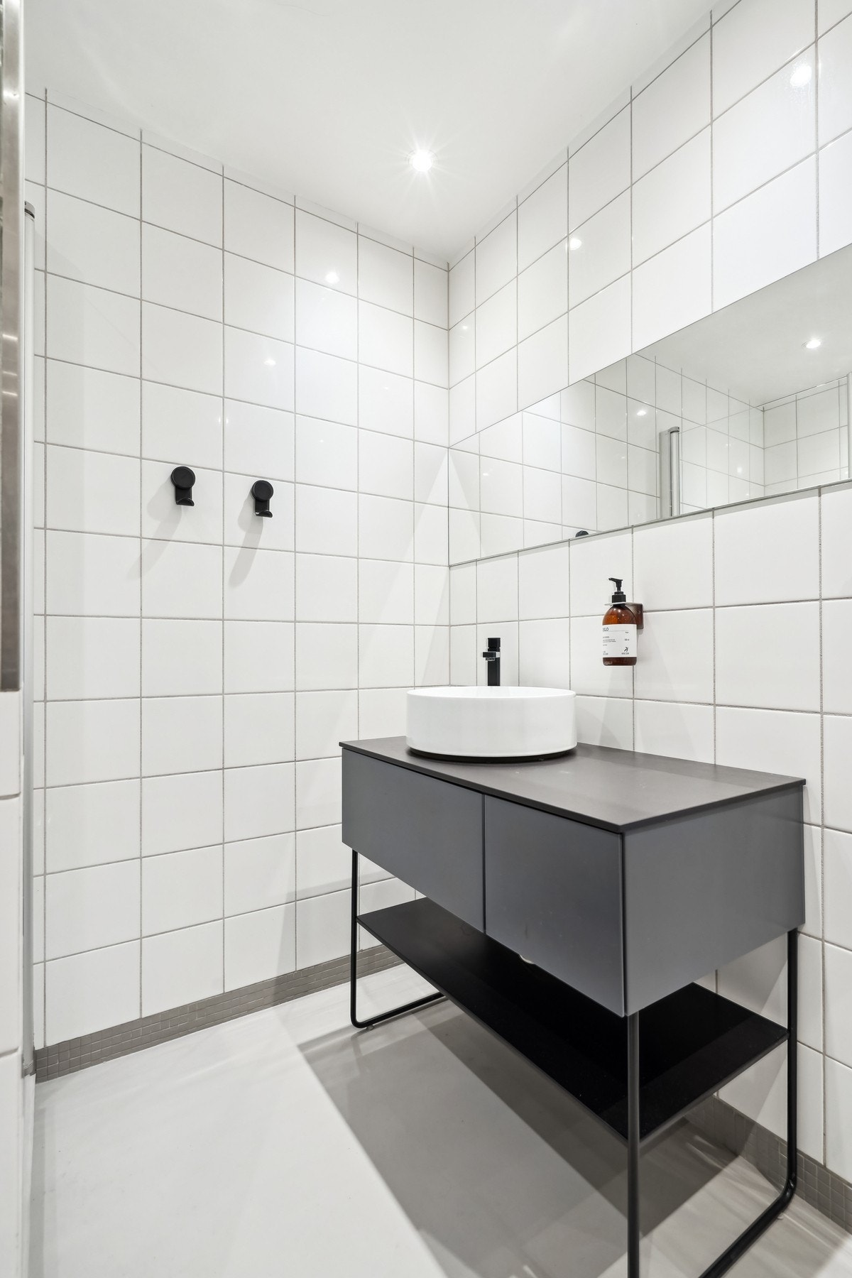 Badet er utstyrt med toalett og servantinnredning fra 2021, dusjnisje med glassdør og speil over servanten. Galleribilde