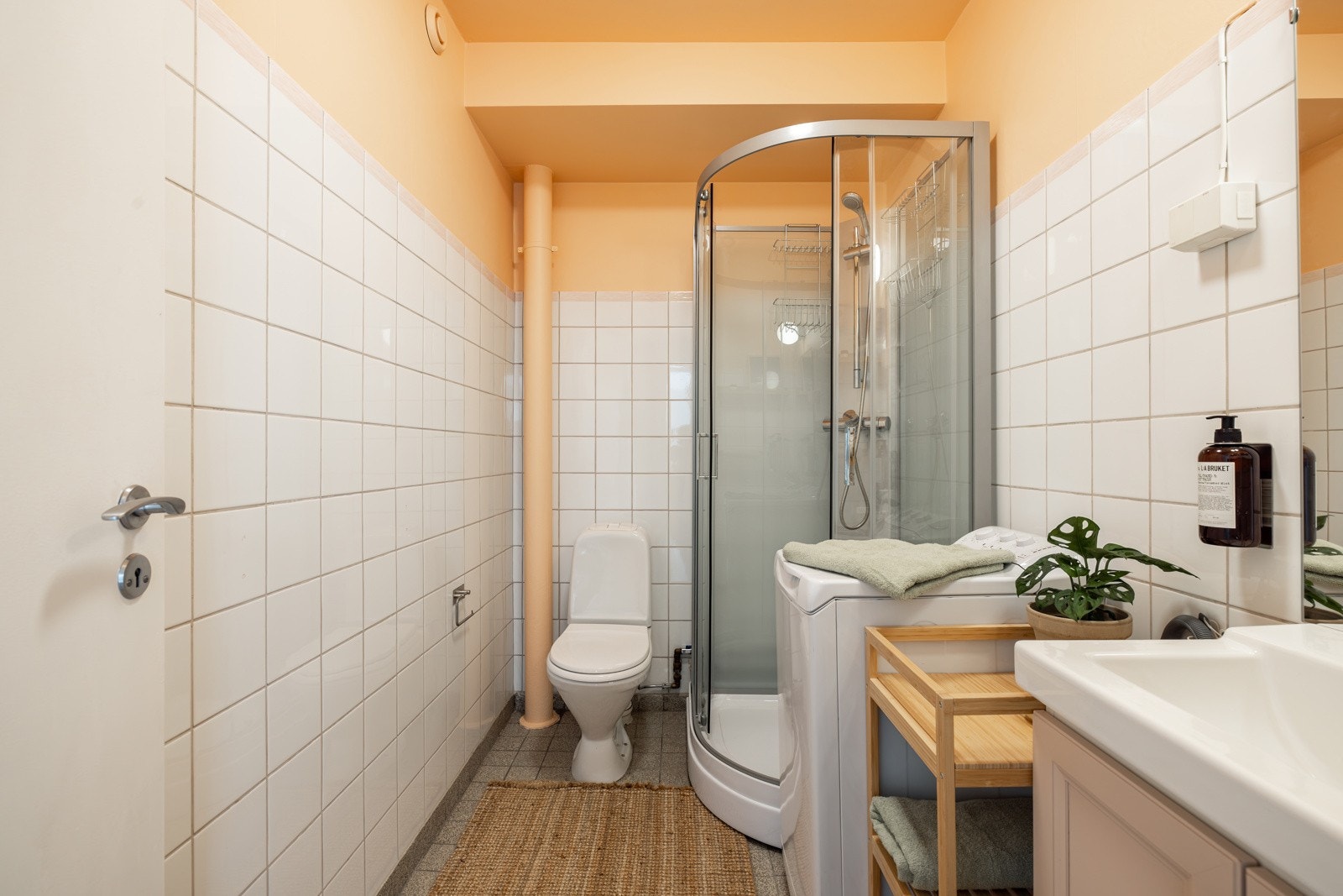 Leiligheten har et sjarmerende baderom. Baderommet har grå fliser på gulv med gulvvarme og hvite fliser på veggene, mens de øvrige flatene er malt i en nydelig ferskenfarge. Galleribilde