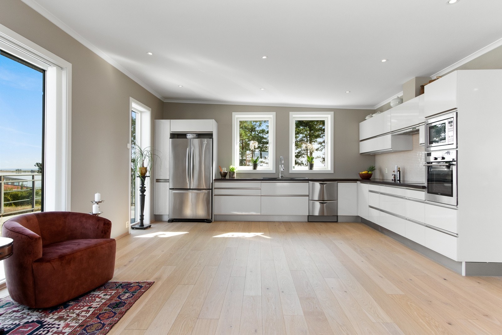 Kjøkkeninnredningen er fra Schmidt og har hvite, slette fronter med sølvfargede grep, kombinert med grå sokkel og sorte benkeplater av laminat. Galleribilde