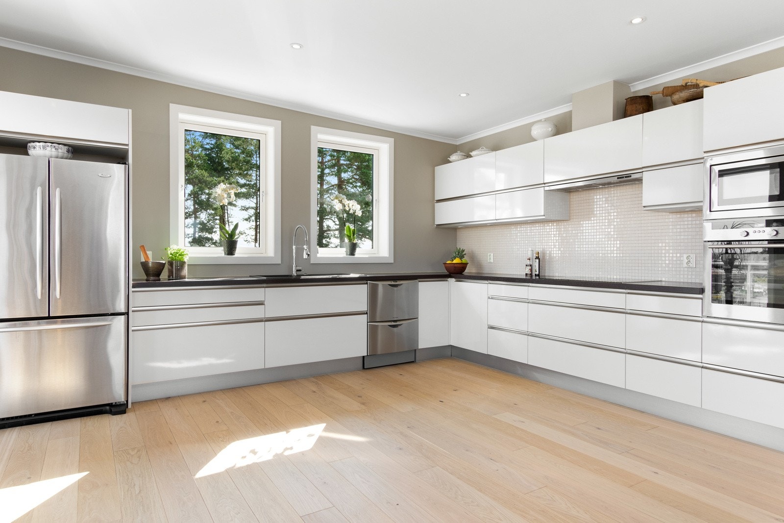 Kjøkkenet har et strømlinjeformet og moderne uttrykk med skap bygget i en tradisjonell og funksjonell hjørneløsning. Galleribilde