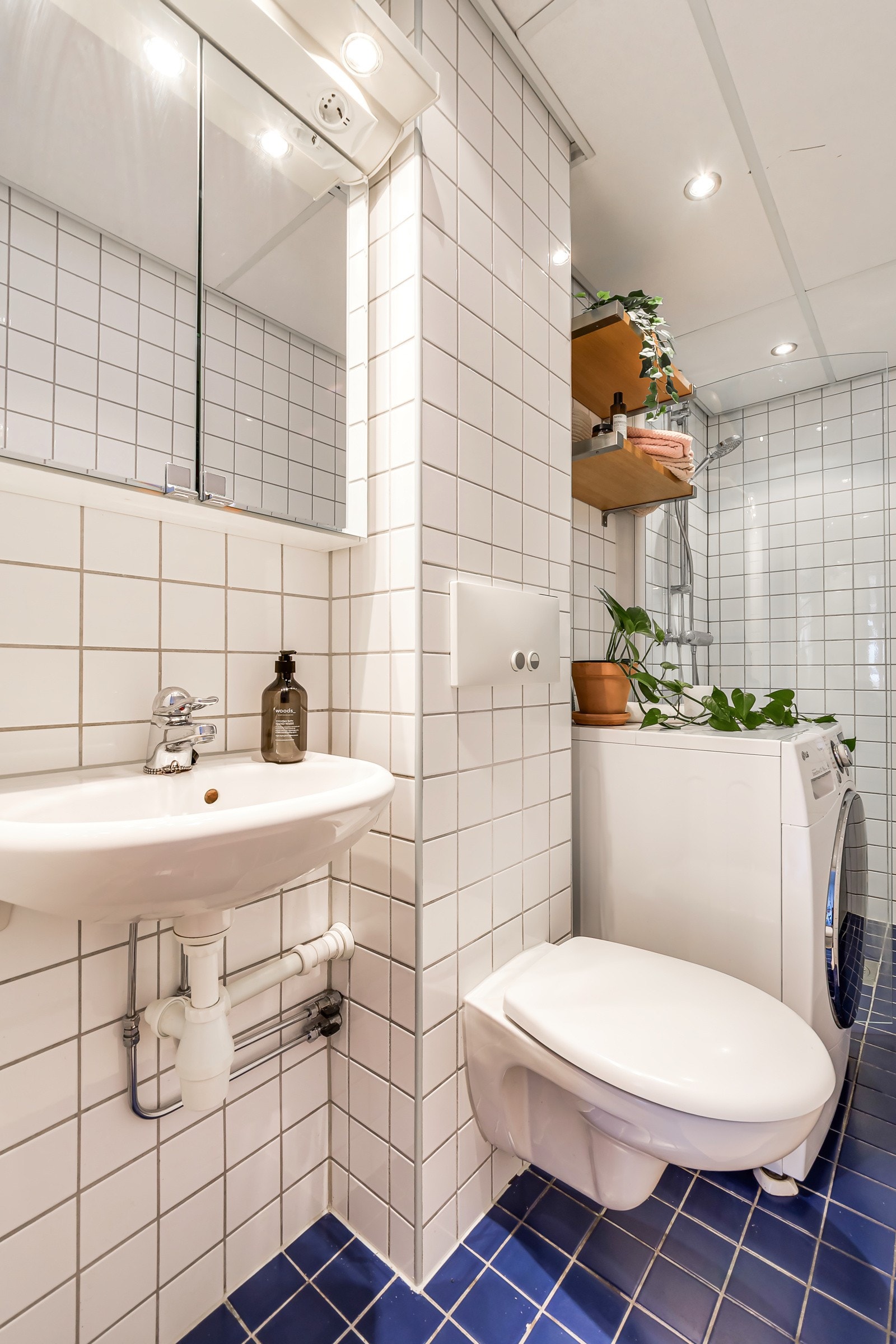 Badet inneholder servant, speilskap med belysning, vegghengt toalett og dusjhjørne med innfellbar dør i glass. Galleribilde