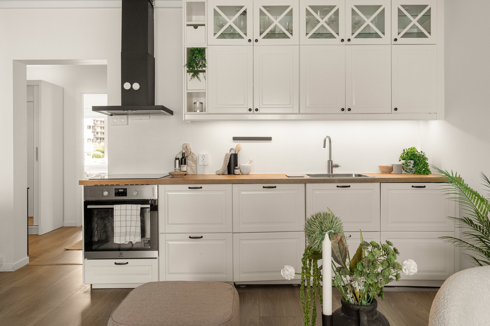 Kjøkken utstyrt med hvite profilerte fronter, eikefinert benkeplate med sponkjerne og nedfelt kum i rustfritt stål, samt opplegg for vaskemaskin. Galleribilde