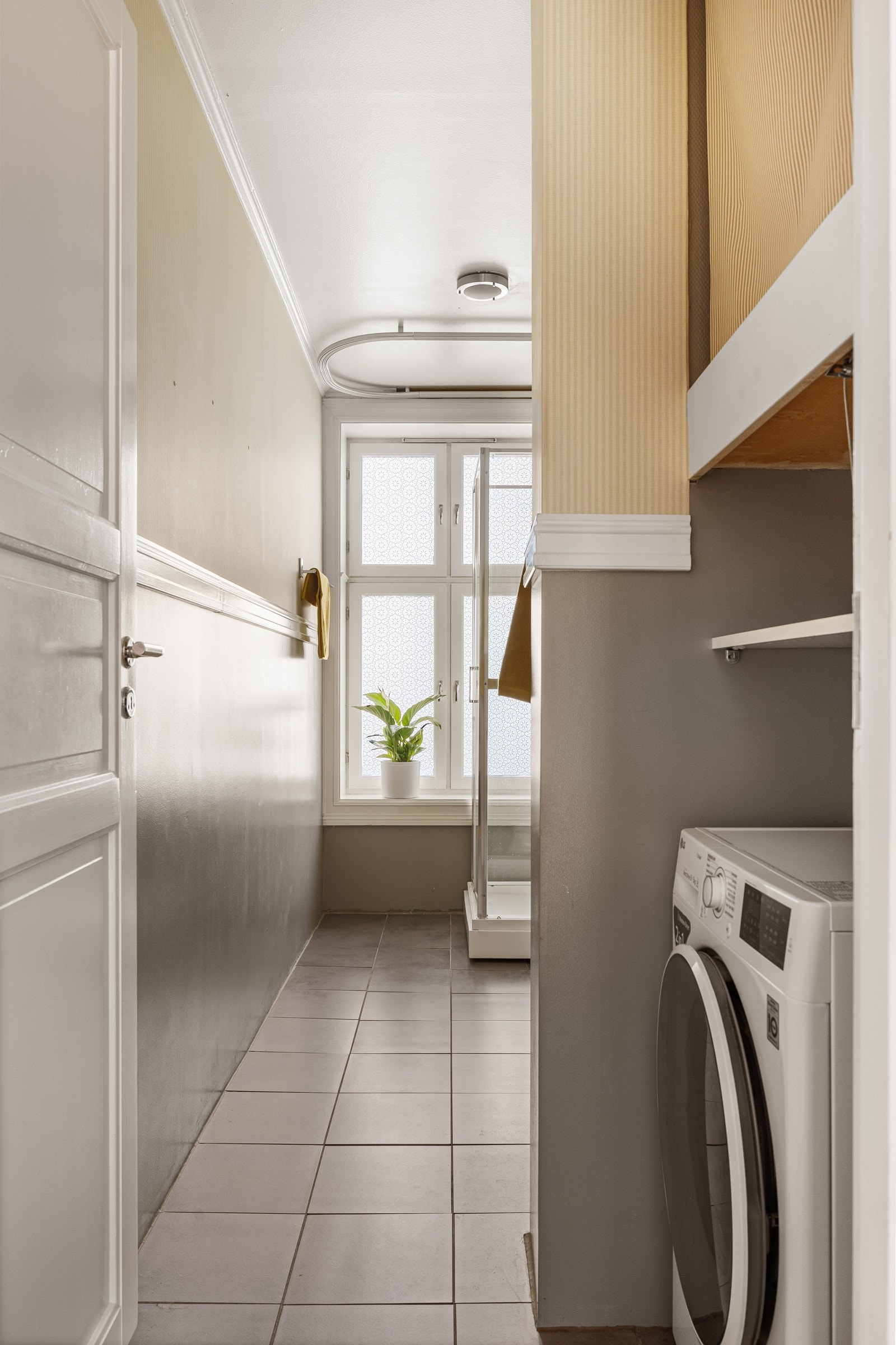 Flislagt, romslig baderom med dusjkabinett med skyvedører og dusjbatteri tilkoblet hånddusj. Galleribilde