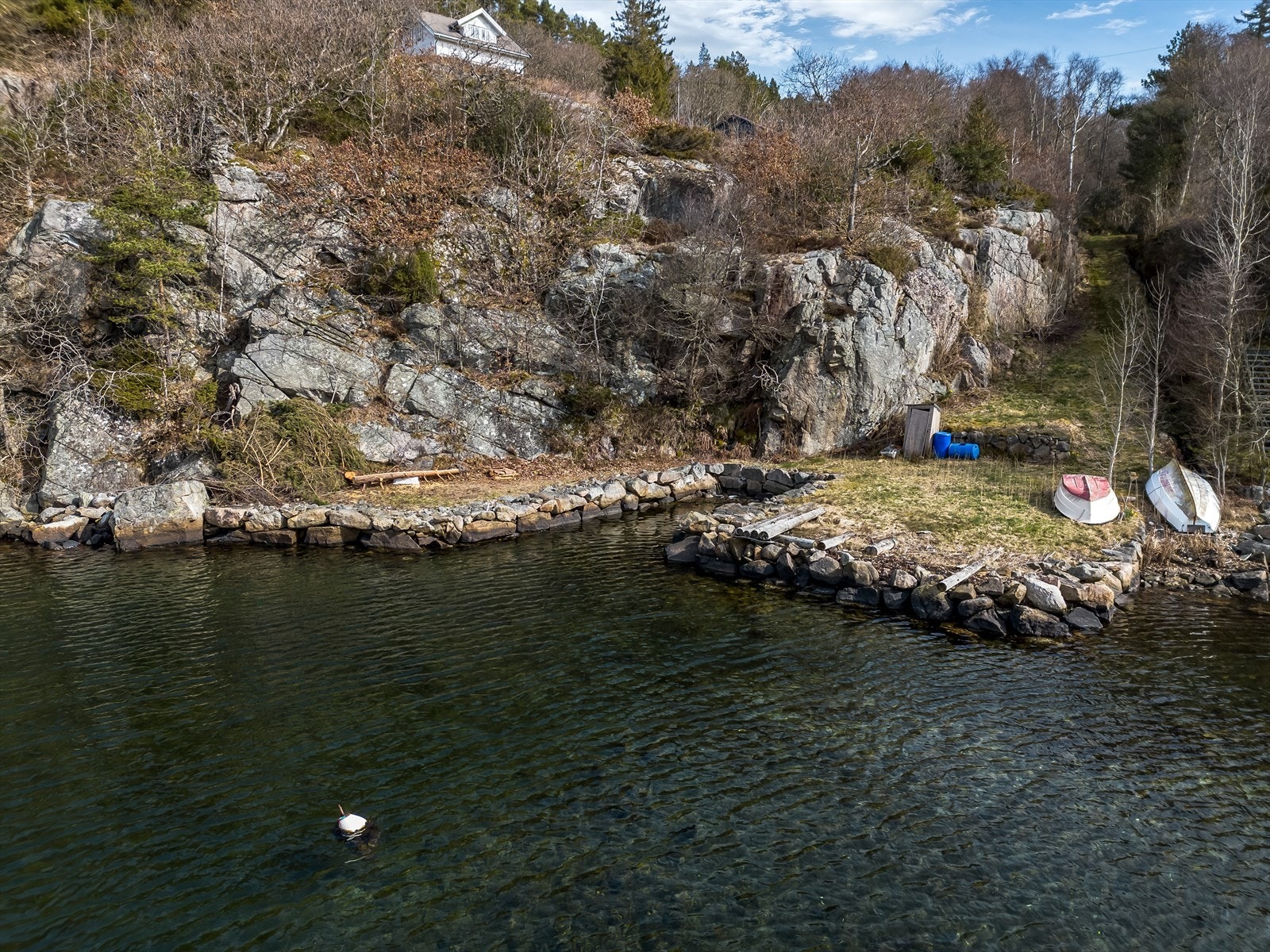 Steinsatt strandlinje med båtstø. Galleribilde